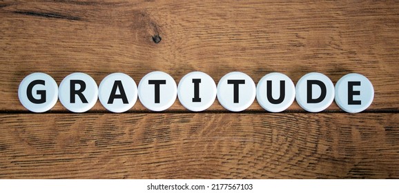 Gratitude Symbol. The Concept Word Gratitude On White Circles. Beautiful Wooden Table, Wooden Background. Business And Gratitude Concept. Copy Space.