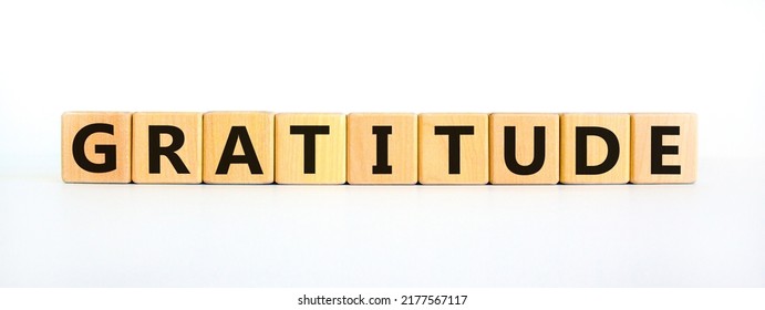 Gratitude Symbol. The Concept Word Gratitude On Wooden Cubes. Beautiful White Table, White Background. Business And Gratitude Concept. Copy Space.