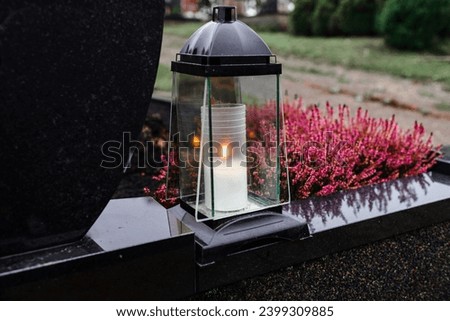 Grave candle light.Graves in a cemetery.Catholic cemetery background. All saints holiday.Grave candles on marble tomb.Gray granite grave.