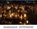 a grave lit with numerous cemetery lights with other illuminated graves in the background on All Saints