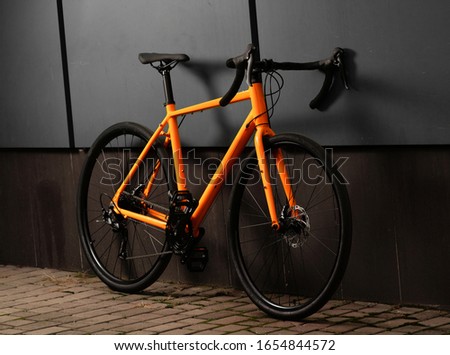 Gravel bicycle. Shiny orange bike for offrad cycling on grey background. Close up.