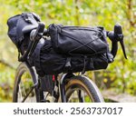 A gravel bike is being packed with essential gear in a lush green forest, showcasing meticulous preparation for an upcoming outdoor adventure.