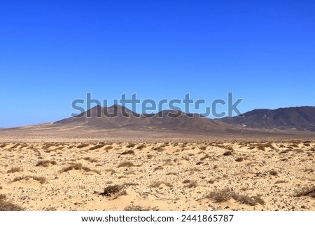 Gravel, dusty road with high volcanic mountains in the background. Jandia, Morro Jable, Fuerteventura, Canary Islands in Spain