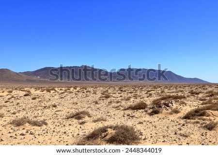 Gravel, dusty road with high volcanic mountains in the background. Jandia, Morro Jable, Fuerteventura, Canary Islands in Spain