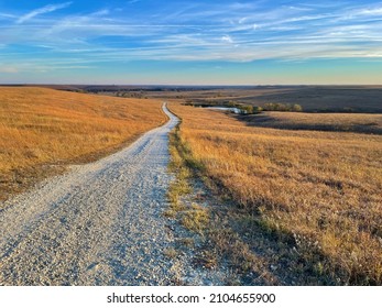 A gravel path leads to the horizon as the sun sets over the Tallgrass Prairie National Preserve in Kansas, USA