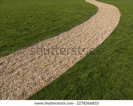 Gravel path on a green lawn curving into the distance, a path to the future