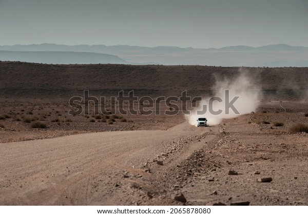 gravel road in desert with moving car by dry
season in Namibia