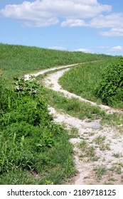 A Gravel Road On A Grassy Hillside. 