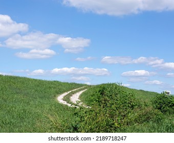 A Gravel Road On A Grassy Hillside. 