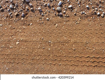 Gravel road surface with a print of a plurality of wheels.