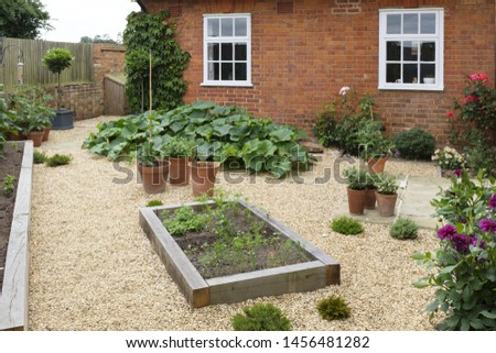 Gravel vegetable garden or back yard with wooden raised beds made from oak sleepers