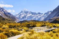 Gravel Walking Track In Hooker Valley To Mt Cook On South Island Of New Zealand With Small Foot Bridge Across Stream.
