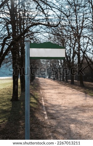 Gravel walkway between avenue of trees with white blank signpost