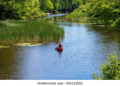 Gravenhurst, Ontario - July 17, 2016: Two male canoeists and a pair of kayakers paddling on a small placid stream near Lake Muskoka.