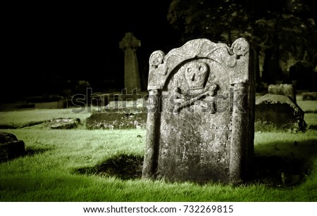 Gravestone with skull and bones in old cemetery, dramatic light