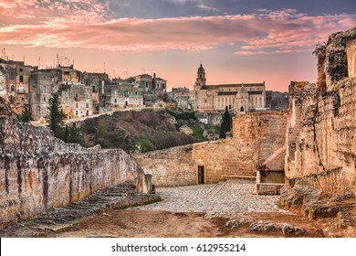 Gravina in Puglia, Bari, Italy: landscape at sunrise of the old town with the cathedral seen from the pathway with the source at the entrance of the ancient aqueduct bridge over the ravine