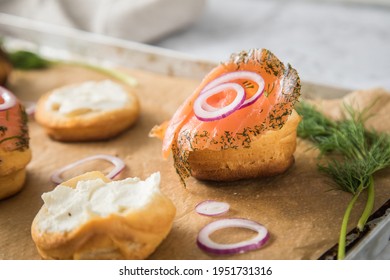 Gravlax A Raw, Marinated Graved Salmon With Dill On Bred Roll Bun With Cream Cheese, Onion Rings On Tray With Baking Paper And Light Marble Background