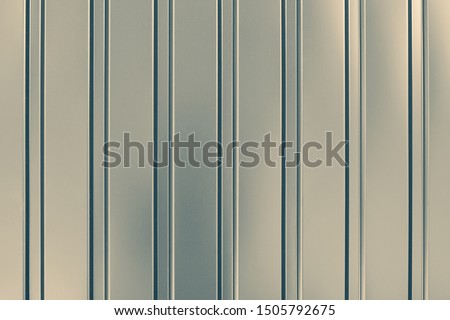 Gray abstract background with stripes. Metallic striped surface. Gold metalline wall siding, cladding. Striated grey shiny fence with glitter. Reflecting metal convex texture. Ribbed backgrounds.