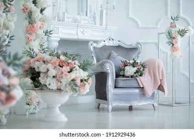 a gray armchair stands in a bright white room decorated with flowers