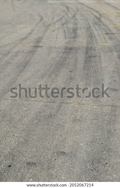 Gray\
asphalt with black tire tracks. An old country road with cracks.\
Curved wheel tracks in a bend in the\
highway.
