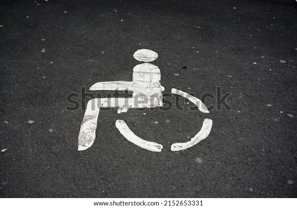 Gray asphalt parking spot with white sign of disabled\
parking 
