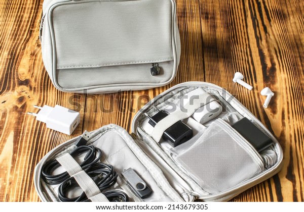 Gray bag, charger handbag, cables, flesh driver,\
power bank organizer for road trip, work vacation, business trip on\
wooden table.