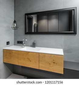 Gray Bathroom With Countertop Basin, Black Mirror And Wooden Cabinet