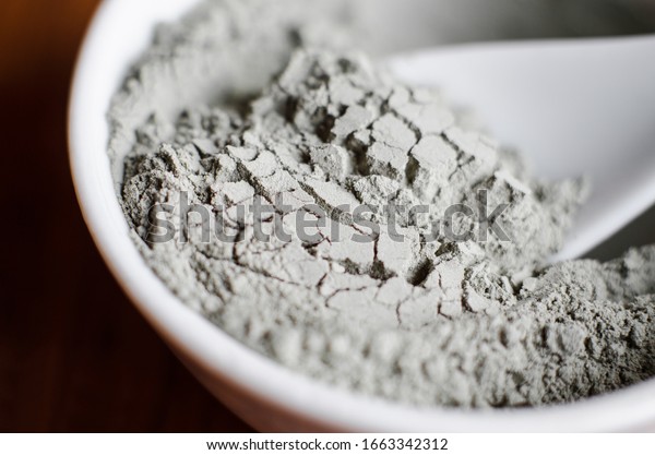 Gray bentonite clay powder in a bowl.\
Diy facial mask and body wrap recipe. Natural beauty treatment and\
spa. Clay texture closeup, selective\
focus.