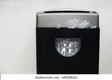 Gray black document shredder with paper inside on the white background.
