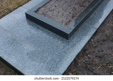 Gray Black Marble Gravestone In Brown Earth On A Grave In A Cemetery