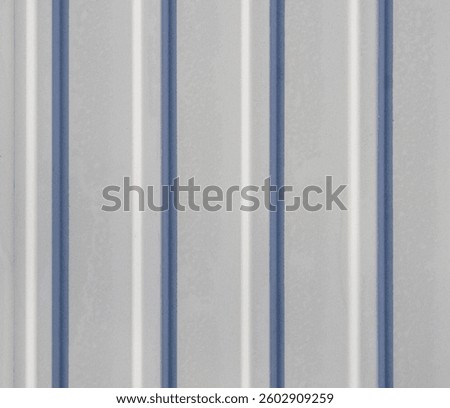 A gray and blue striped surface, possibly a metal or wooden panel. The stripes are evenly spaced and create a sense of order and structure. Scene is calm and composed, with the blue