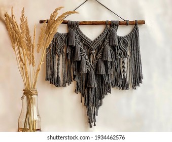 Gray boho macrame with tassels on white background. Bohemian wall hanging made of cotton threads in dark grey color using the macrame technique for home decor. Scandinavian home wall decor.