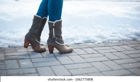 Gray boots with heels with white fur and buckles on paving stones with snow - Shutterstock ID 1062775808