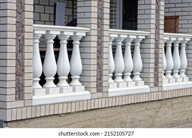 Gray Brick Wall Of A Private House With A Row Of White Concrete Columns On The Street