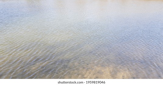 Gray and brown lake water surface with slight ripples from light wind and small shadows on the water (angle, texture). - Shutterstock ID 1959819046