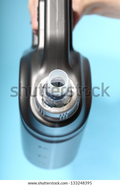 Gray\
canister with car engine oil in hand blue\
background