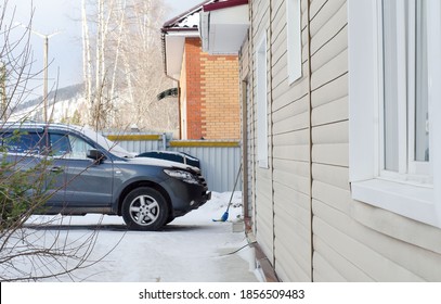 Gray Car Is Parked In Front Of Private House With White Walls. Winter Landscape Of Personal Home Ownership.