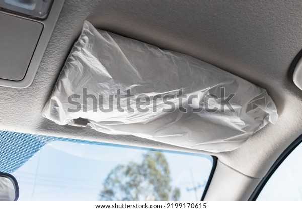Gray car sun visor with\
plastic wrap