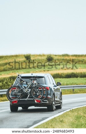 Gray car transporting two bicycles on a special trunk mounted bike rack