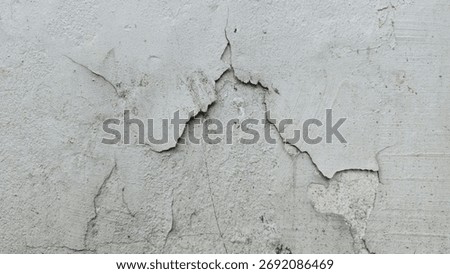 Gray cement wall surface with cracks and peeling paint revealing inner layers, showing rough texture and aging details, perfect for background or vintage design.