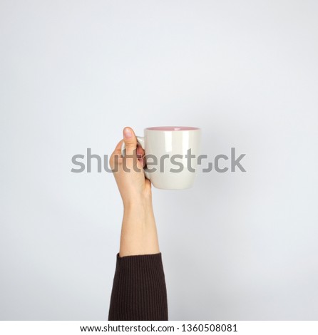 Foto Bild brauner Keramikbecher in weiblicher Hand auf weißem Hintergrund