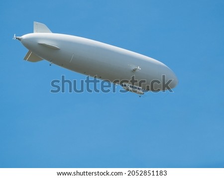 Gray cigar-shaped airship flying in clear blue sky