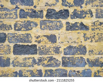 Gray cinderblock wall with yellow peeling paint