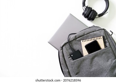 Gray city backpack with laptop, smartphone, notepad, external ssd and headphones on white background. Lifestyle concept with gadgets. Ð¡oncept of a modern student's backpack. White background