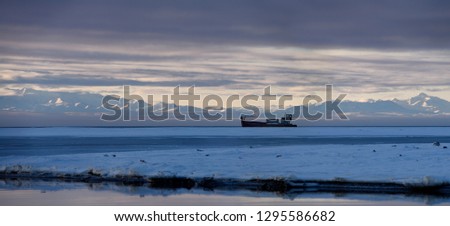 Gray clouds with abandoned whaling ship on Barter Island Kaktovik Lagoon Alaska with Brooks Range mountains