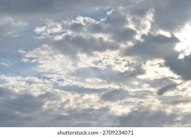 Gray clouds pierced by rays of sunlight, a sky with some traces of blue sky.