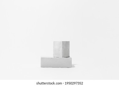Gray cocncrete cube and parallelepiped shaped pedestals on white background with copy space, side view. Podium mockup for products. Advertising template. Stone platform. Abstract geometric pedestal.