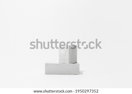 Gray cocncrete cube and parallelepiped shaped pedestals on white background with copy space, side view. Podium mockup for products. Advertising template. Stone platform. Abstract geometric pedestal.