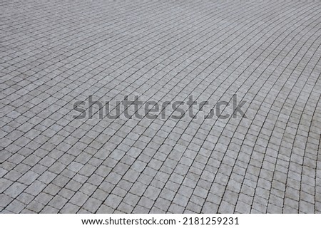 Gray color paving slabs in the pedestrian street sidewalk. Rough cobblestone pattern with many square shaped stones close up