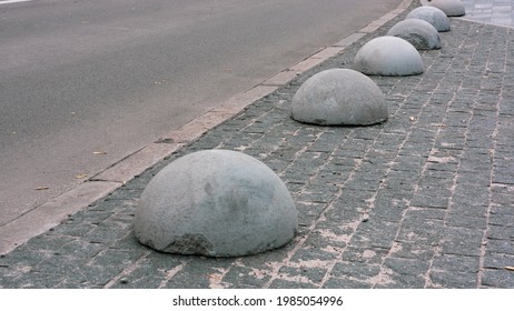 Gray concrete anti-parking hemispheres at the sidewalk